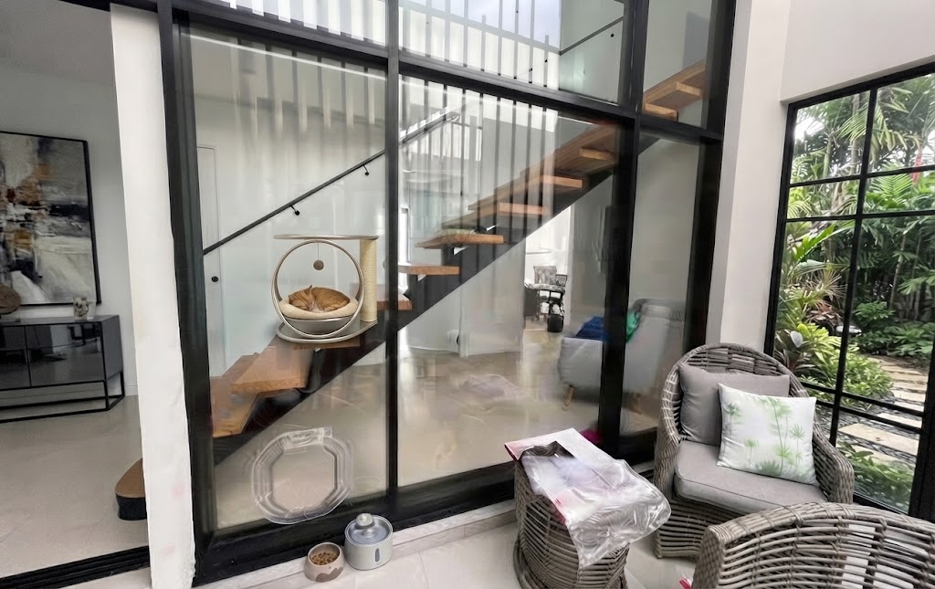 Clear Dogwalk Slim Line dog door installed in a glass aluminium frame beside a staircase