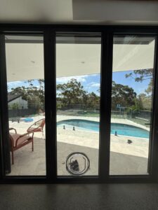 Dogwalk Intermediate Slim Line glass-fitting dog door installed in a sliding glass door overlooking a swimming pool