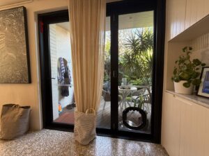 Dogwalk Medium dog door in black fitted into a black-framed glass door, looking through to the garden